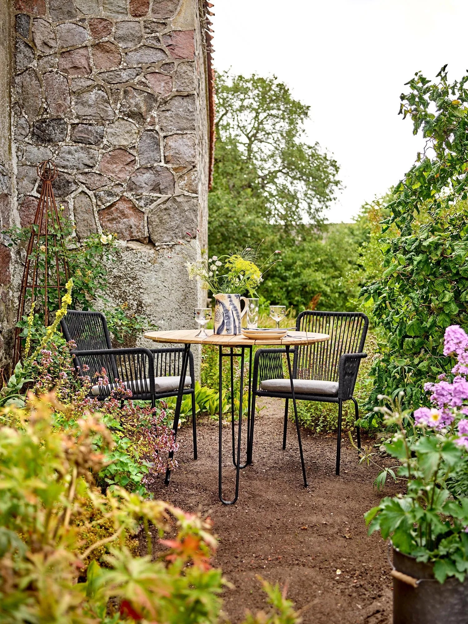 Eleganter Esstisch aus Teakholz mit schwarzem Metallgestell, ideal für stilvolle Outdoor-Dinner.