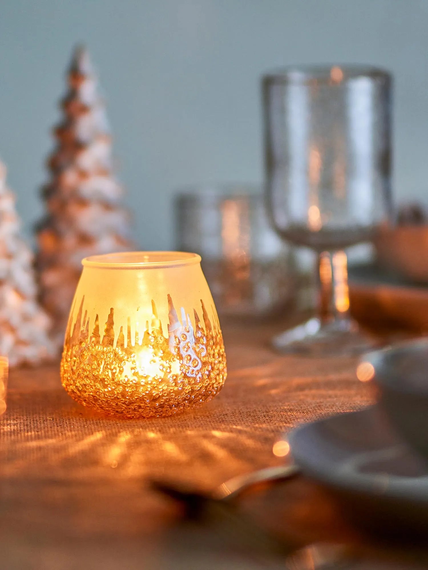 Eleganter Teelichthalter aus recyceltem Glas mit goldenen Akzenten, die warmes Licht reflektieren und Nachhaltigkeit verkörpern.