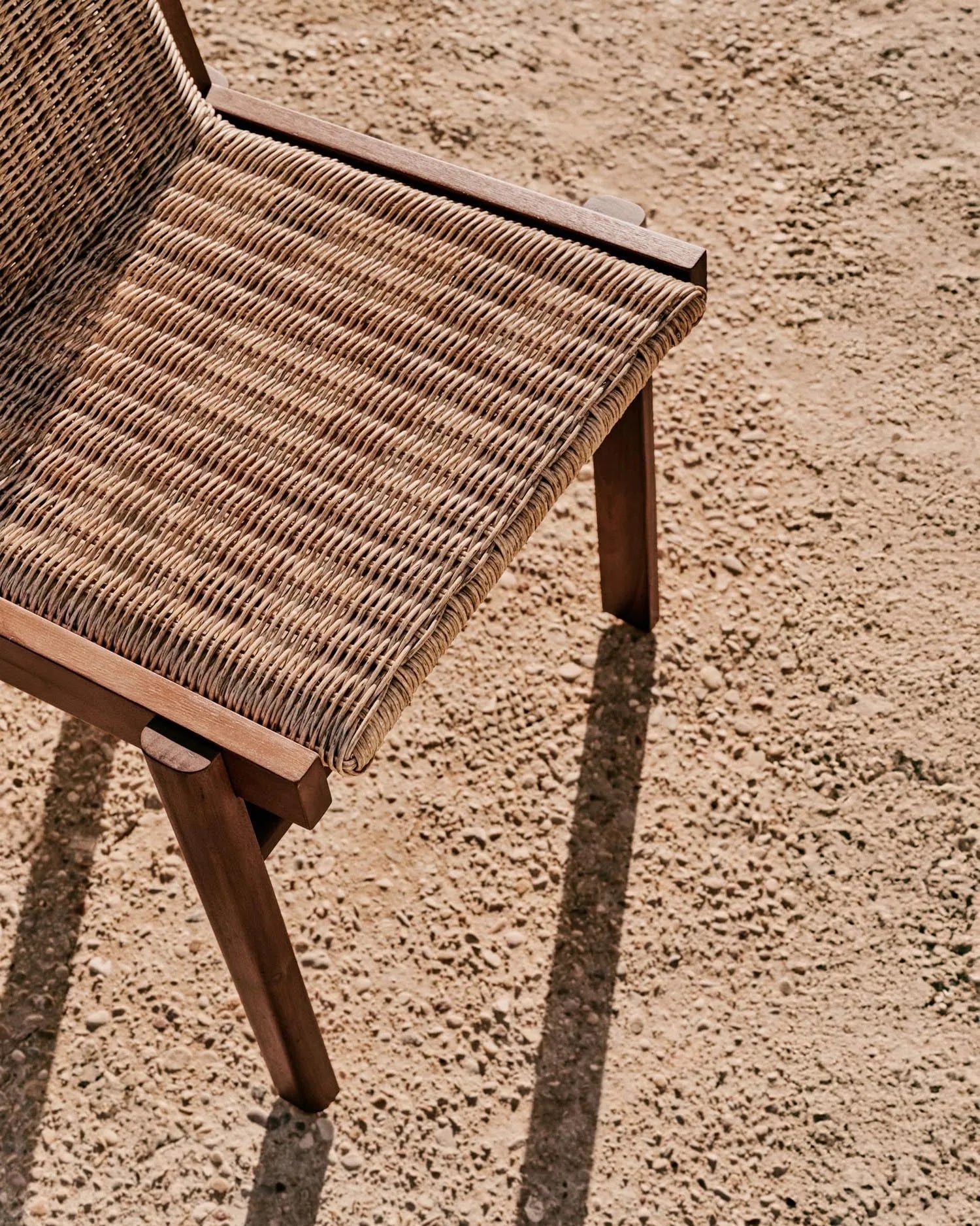 Eleganter Stuhl aus Teakholz und Rattan, nachhaltig und wetterfest, ideal für stilvolle Outdoor-Bereiche.