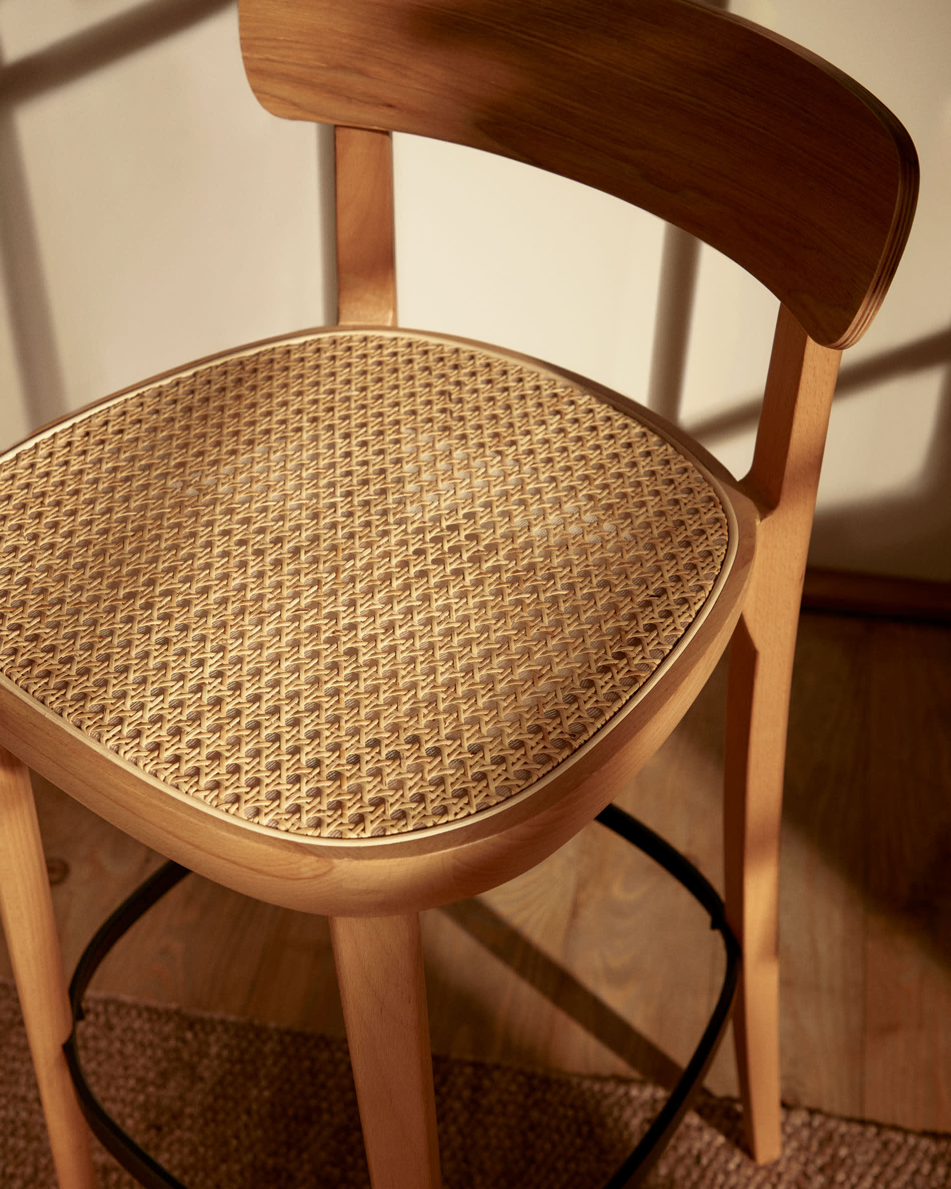 Der Romane Hocker vereint Buchenholz, Eschenfurnier und Rattan zu einem eleganten, stabilen Sitzmöbel für moderne Kücheninseln.